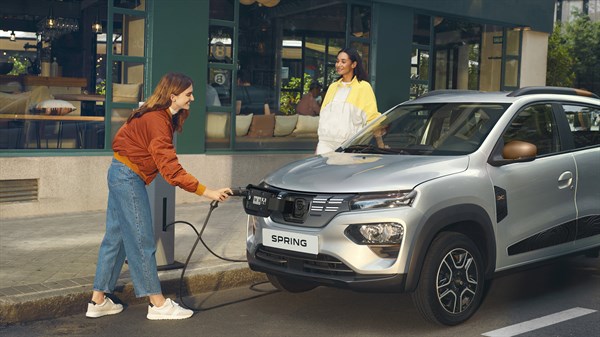 a woman is charging the dacia spring and her friend watching her